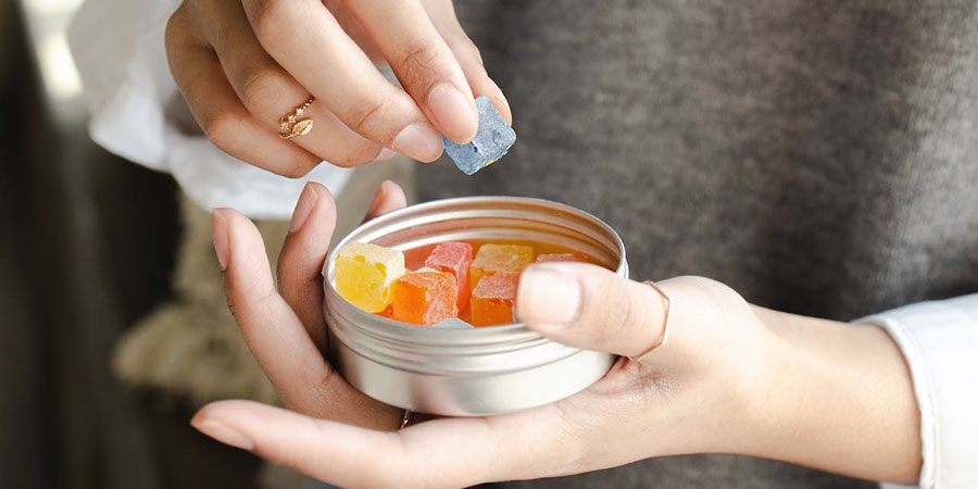 close up of a person's hands holding a tin can of gummies